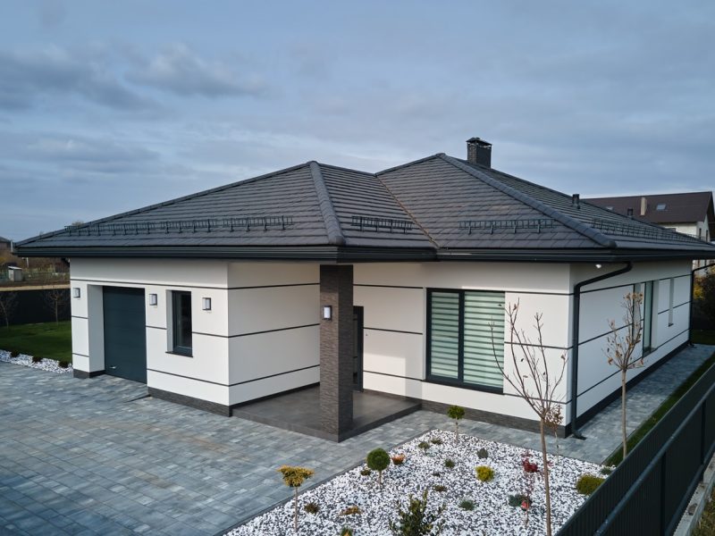 New residential house cottage and attached garage with big paved fenced yard on sunny day in modern suburban area. Real estate property concept.