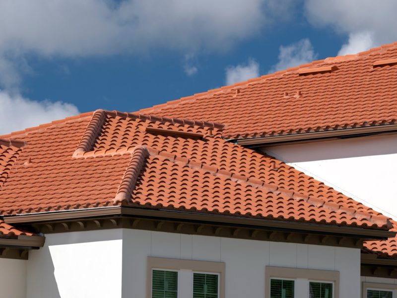 Closeup of house rooftop covered with ceramic shingles. Tiled covering of building
